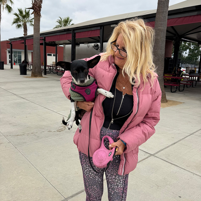 et owner holding a small dog after receiving care during a community veterinary outreach event.